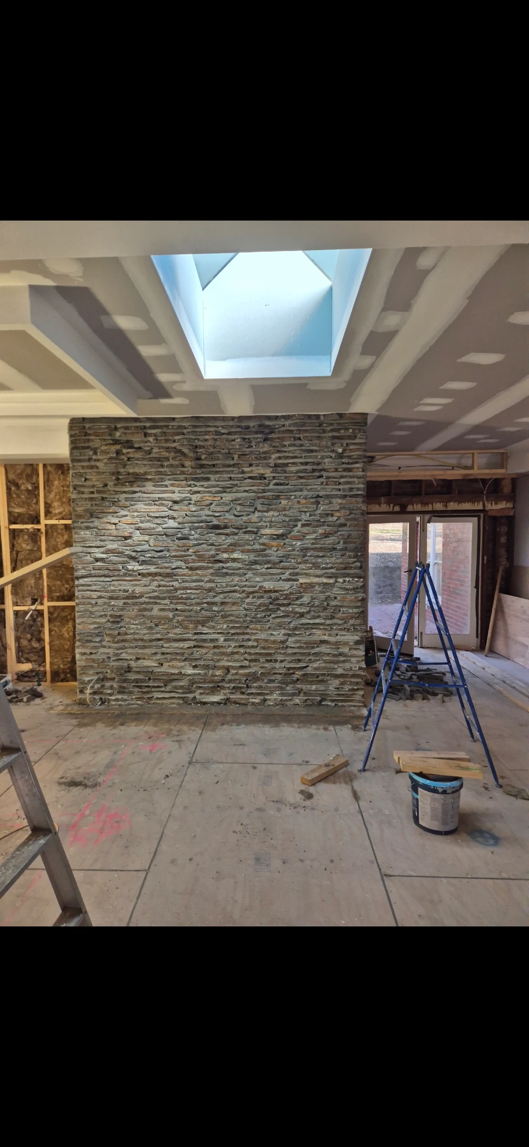 Hayden's stacked-stone interior feature wall beneath a skylight during construction