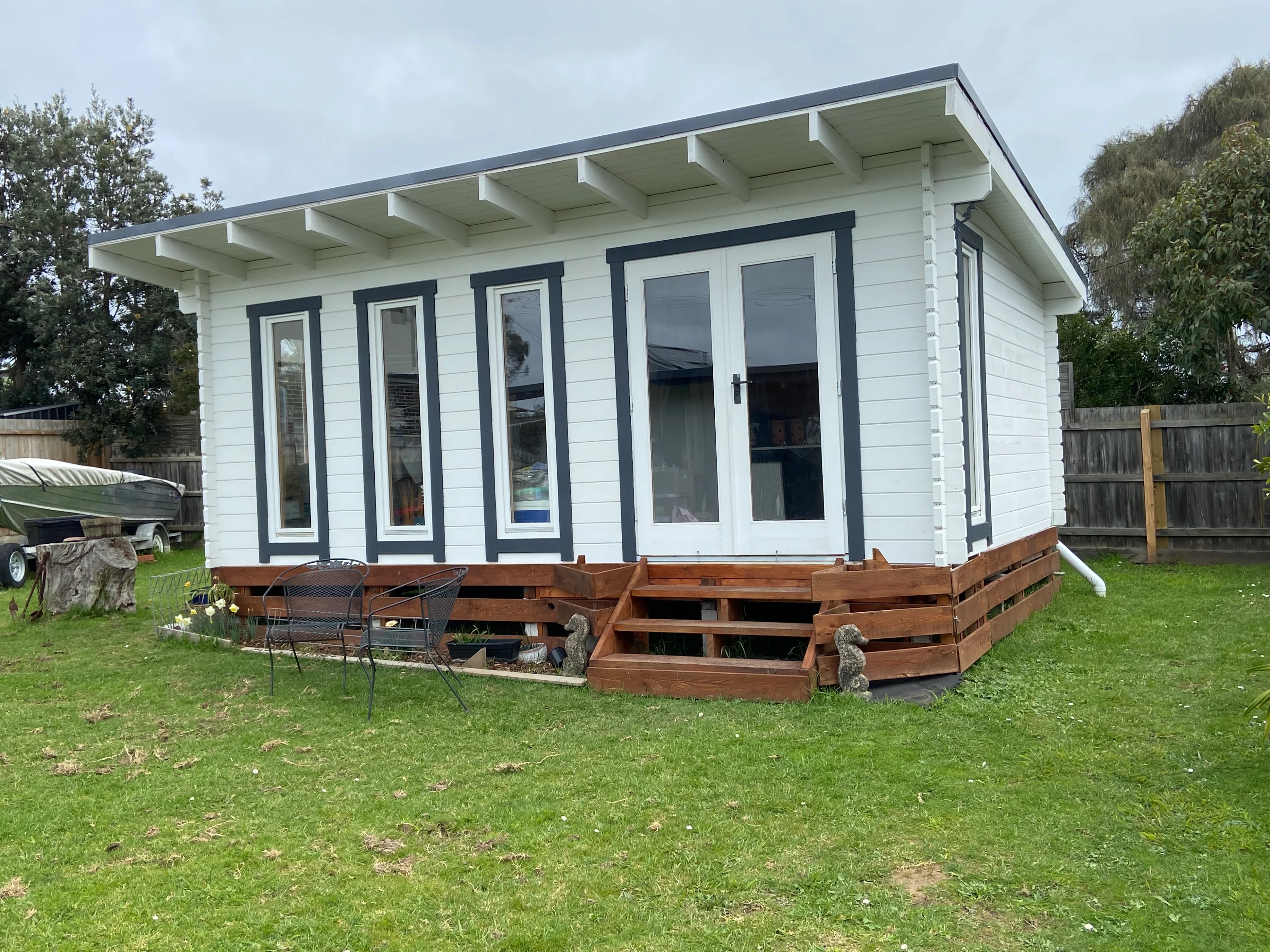 Karen's white backyard studio with timber decking and steps, viewed from an angle